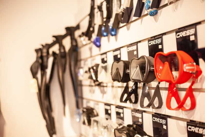A wall of dive masks and fins on display in a dive shop, ready to try on