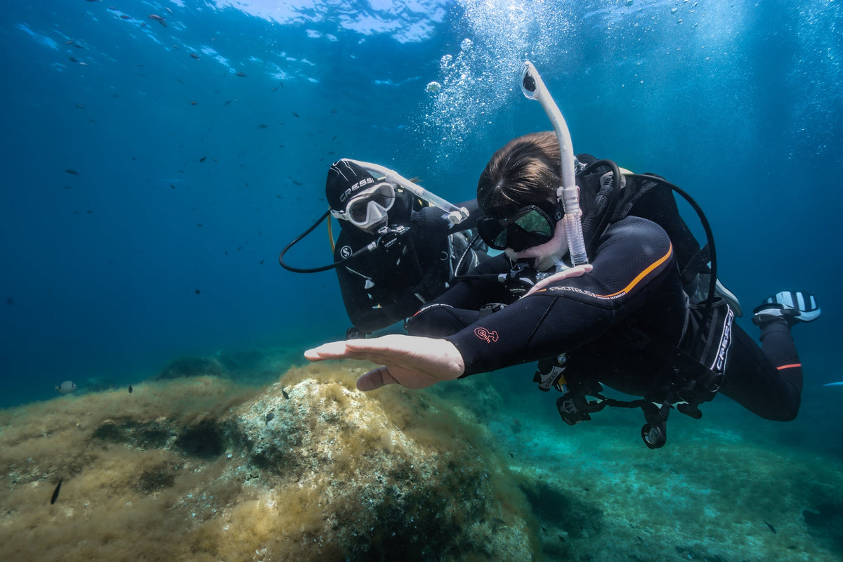 An instructor demonstrating a skill to a student diver underwater during a PADI training dive