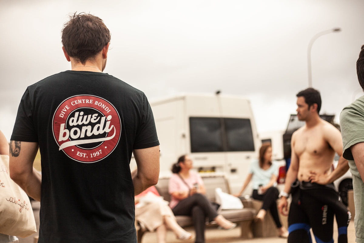 A Dive Centre Bondi team member in a dive bondi T-shirt with divers getting ready beside the dive van