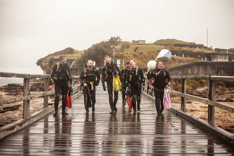 Dive Centre Bondi instructors and divers laughing together on the jetty at Bondi after a dive